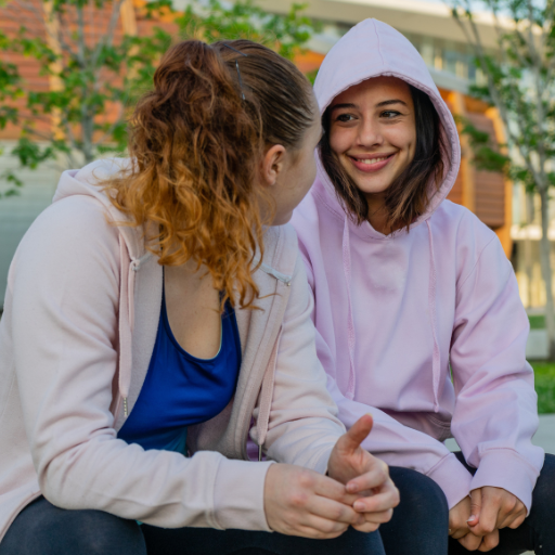 Two women sitting on a bench having a conversation outside | Featured image for the NDIS Providers YouthKan Page of Karakan.